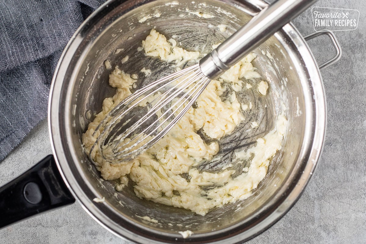 Saucepan with combined cream cheese and butter with a whisk.