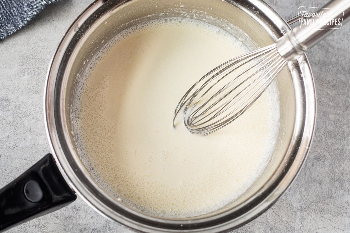 Sauce pan with whisk and a cream sauce base.