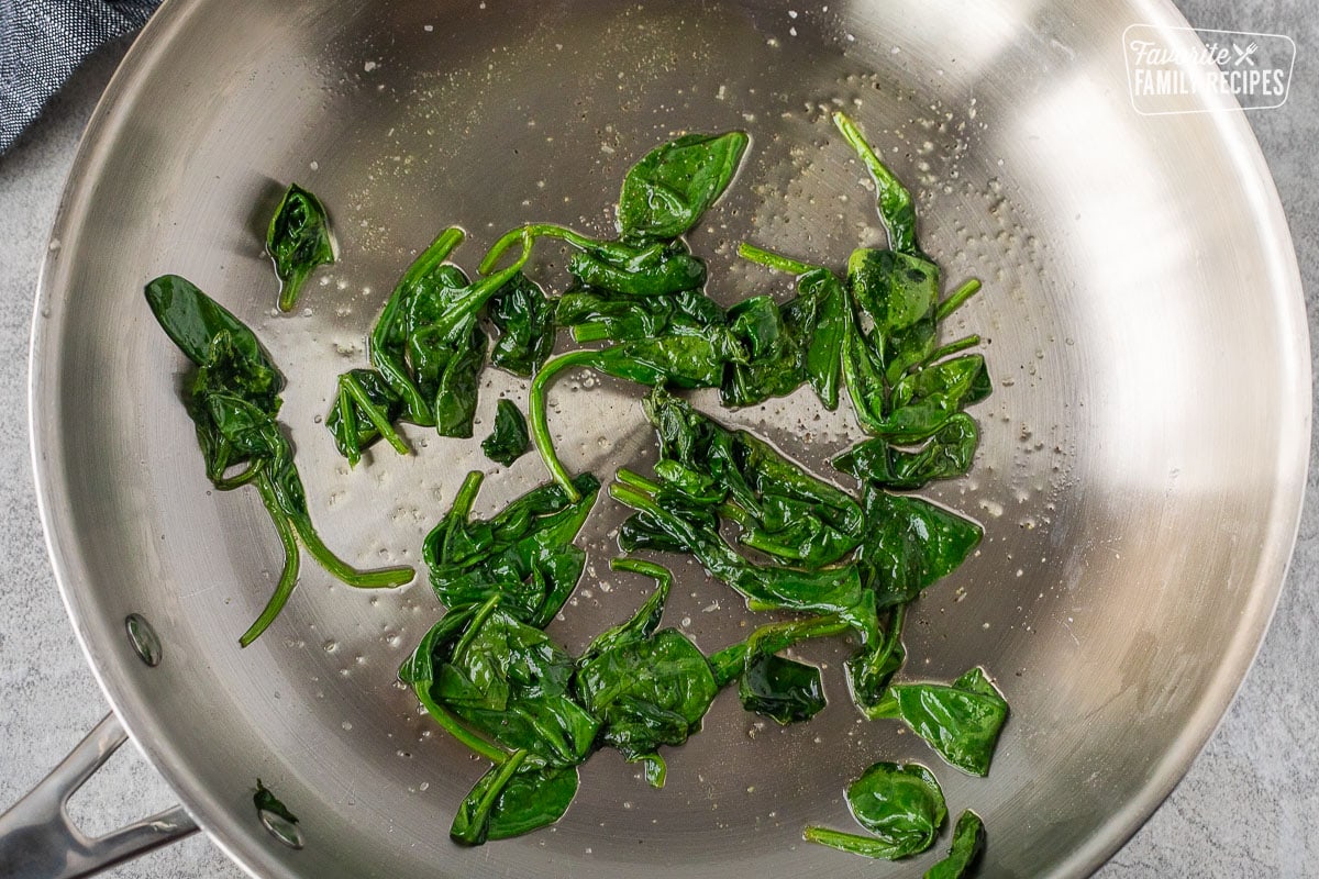 Skillet with cooked spinach.