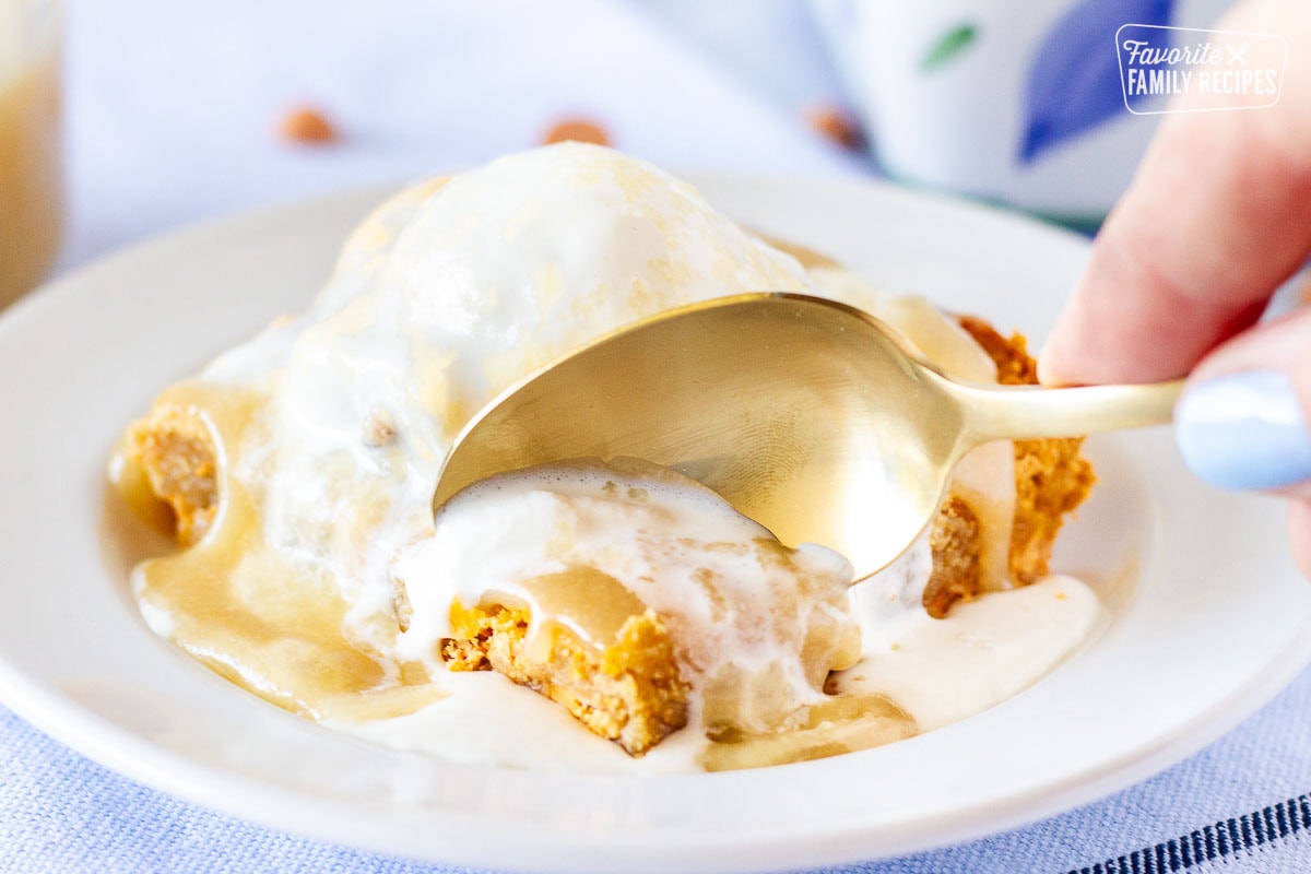 Spoon scooping out a bite of Applebee's maple butter Blondie with ice cream and caramel sauce on top.