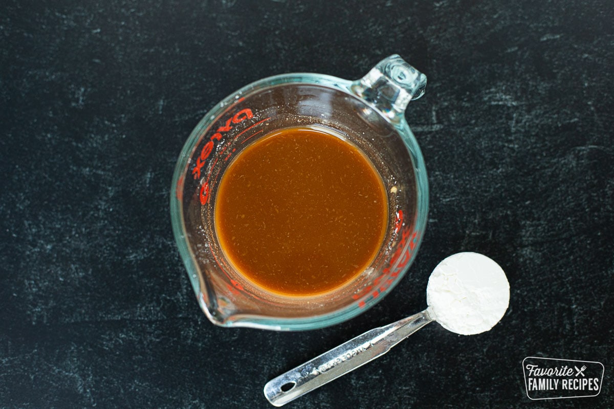 A sauce made from beef broth, soy sauce, and corn starch in a glass measuring cup