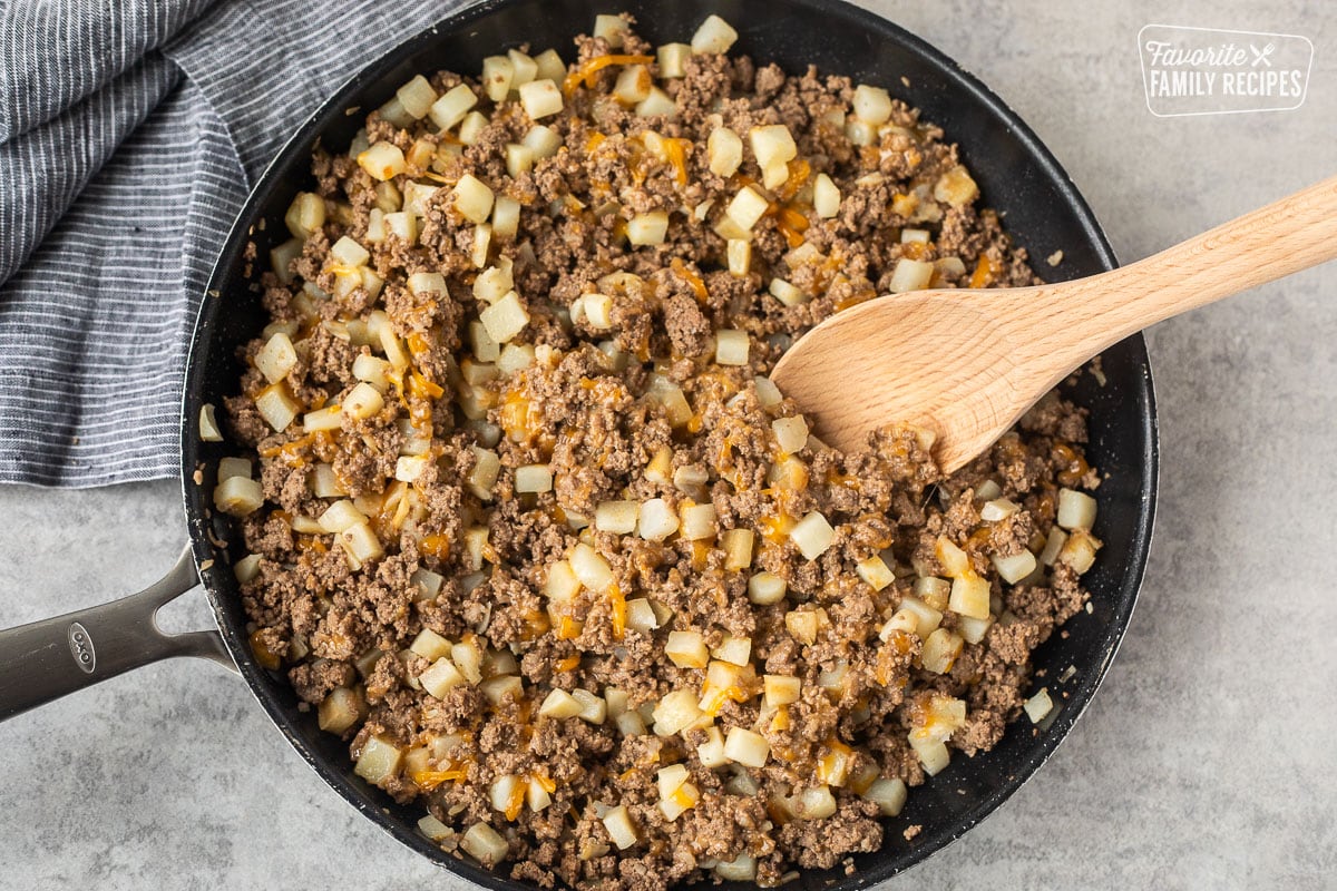 Skillet with ground beef, hash brown potatoes and cheddar cheese.