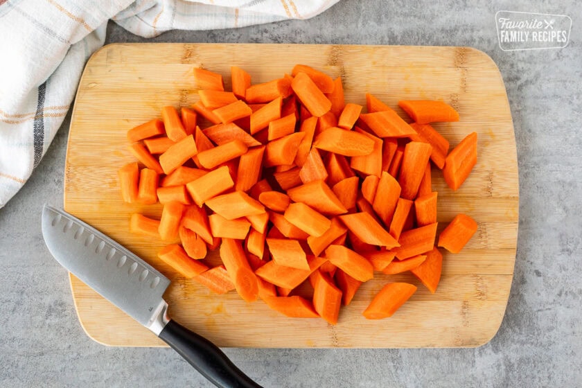 Cut carrots on a cutting board with a knife.