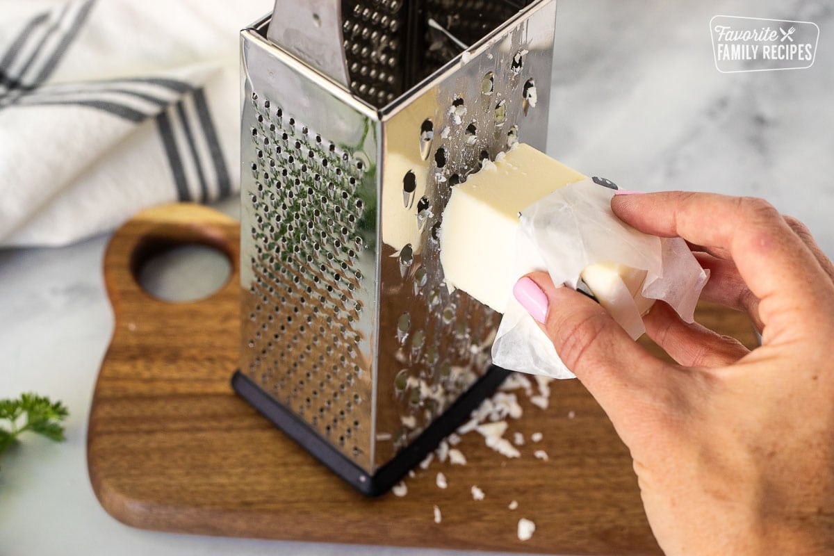 Grating a frozen cube of butter on a cutting board.