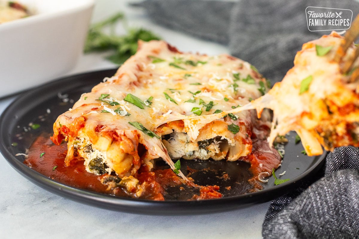 Chicken and Spinach Manicotti on a plate with a fork pulling back a piece.