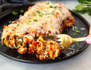 Cutting into a Chicken and Spinach Manicotti shell with a fork.