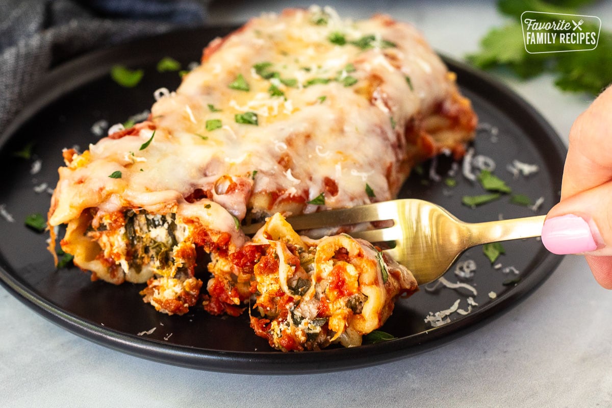 Cutting into a Chicken and Spinach Manicotti shell with a fork.