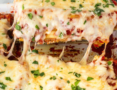 Lifting Chicken and Spinach Manicotti in a baking dish.