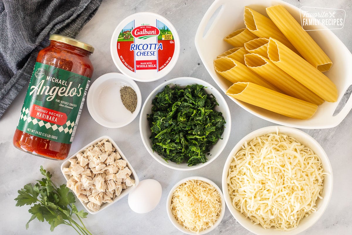 Ingredients to make Chicken and Spinach Manicotti including manicotti noodles, mozzarella cheese, parmesan cheese, spinach, salt, pepper, ricotta cheese, marinara sauce, diced chicken and egg.