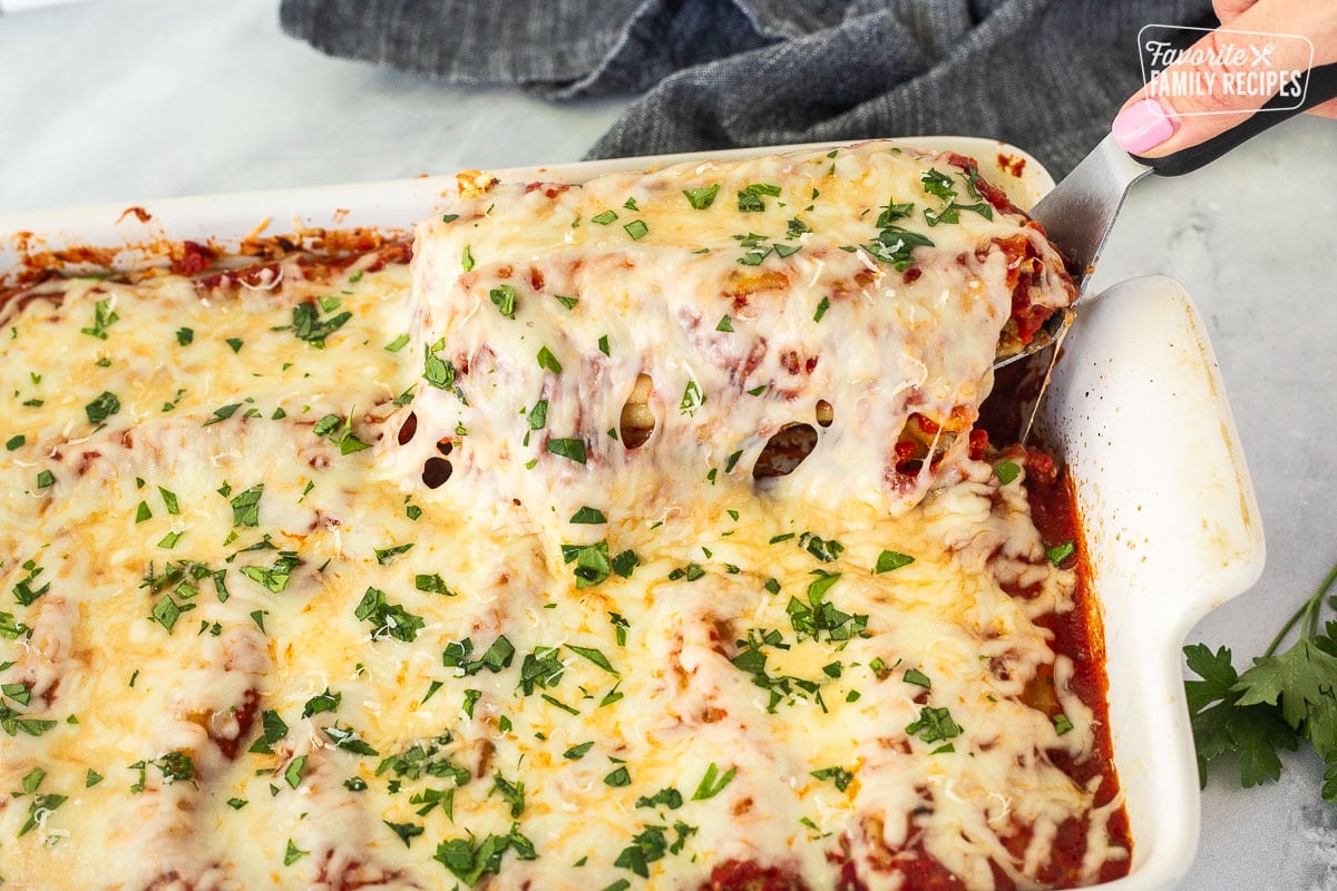 Lifting up Chicken and Spinach Manicotti shells from baking dish.