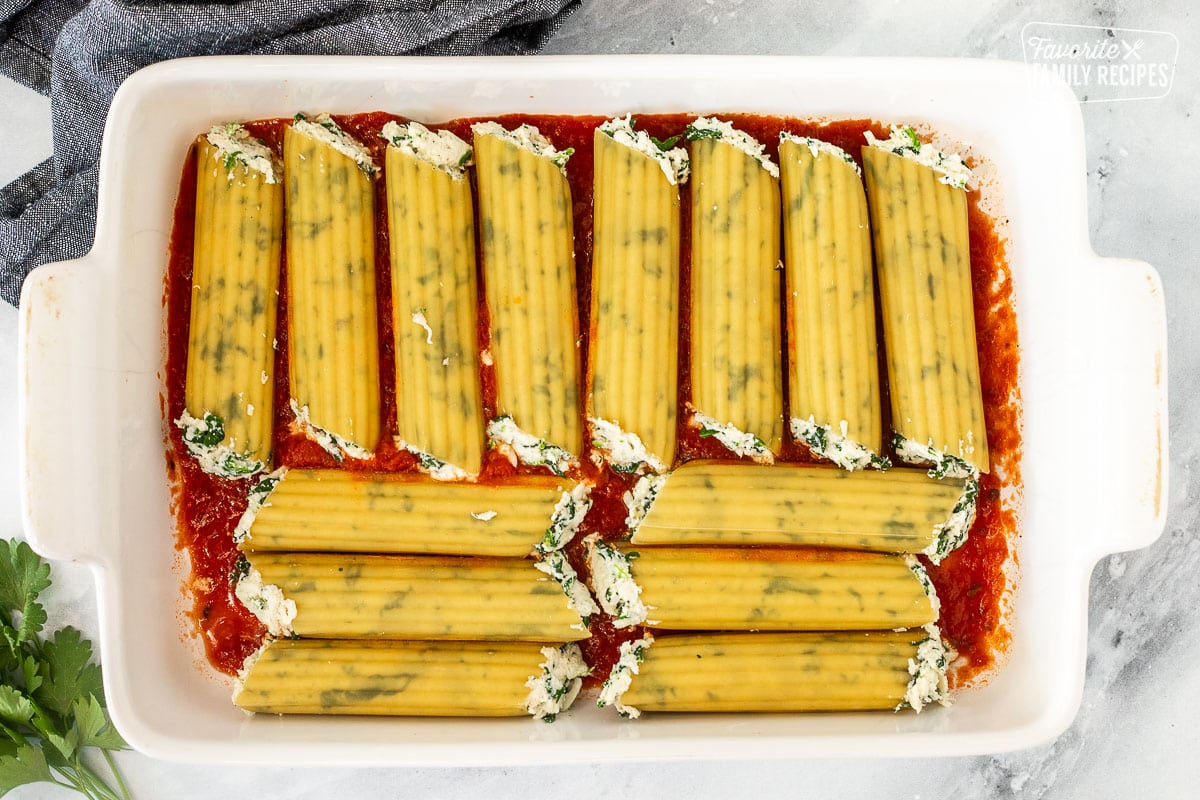 Baking dish with filled unbaked manicotti shells.