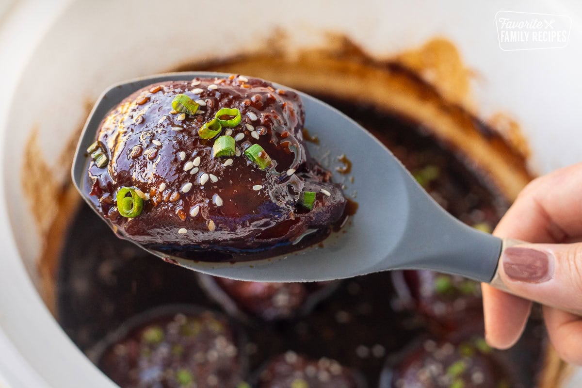 Crockpot Hawaiian chicken held up in a spoon.