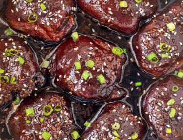 Crockpot with cooked Hawaiian chicken thighs, garnished with green onion and sesame seeds.