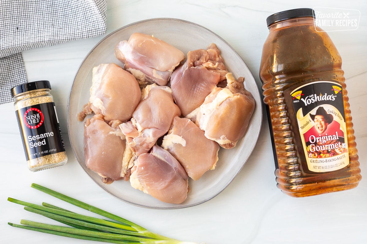 Ingredients to make crockpot, Hawaiian chicken, including Mr. Yoshida's sauce, chicken thighs, sesame seeds, and green onion for garnish.