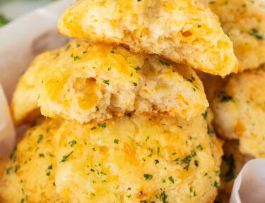 Basket of Cheddar Bay Biscuits with one cut in half.