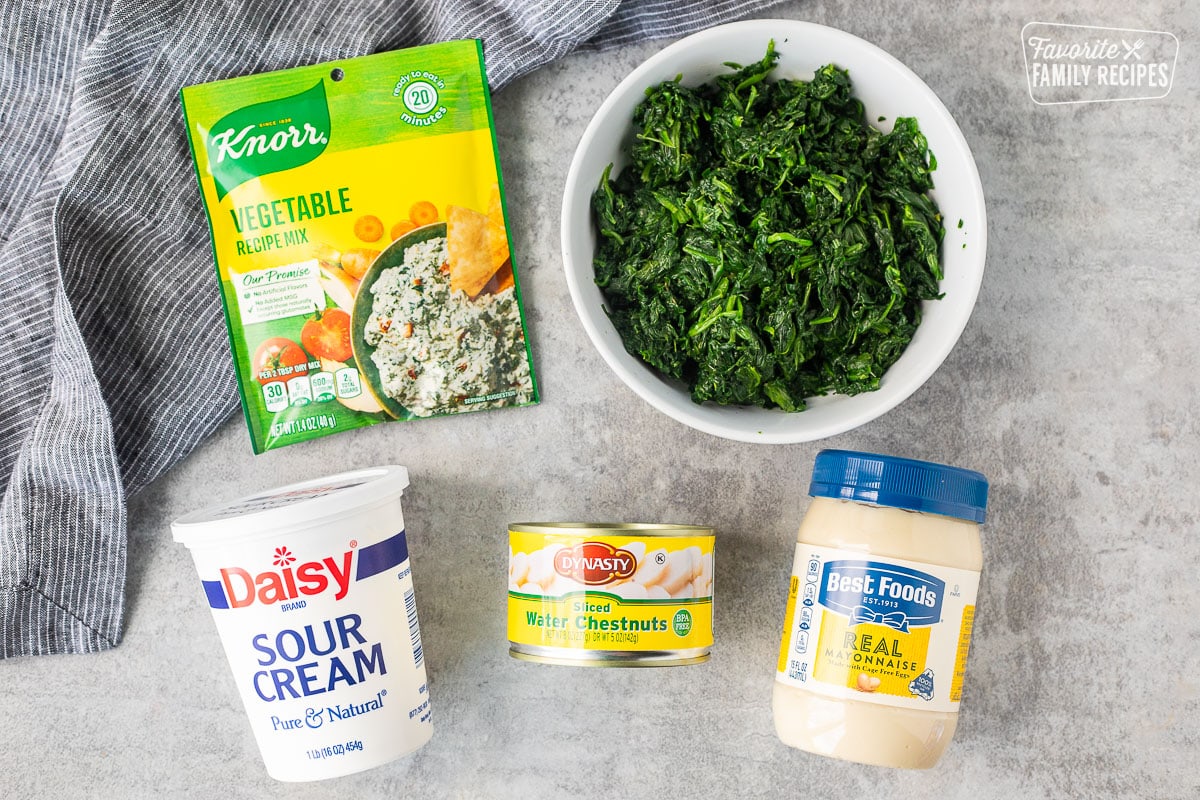 Ingredients to make easy spinach dip including Knorr vegetable mix, mayonnaise, water chestnuts, spinach and sour cream.