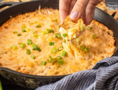 Dipping a slice of bread into a skillet of Hot Crab Dip.