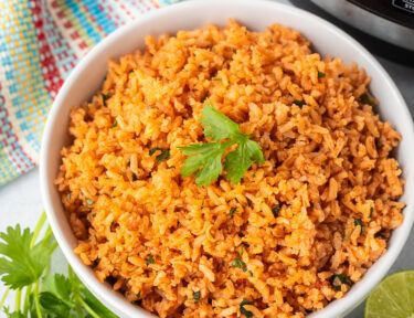 Instant pot Mexican rice in a bowl with cilantro and fresh limes on the side.