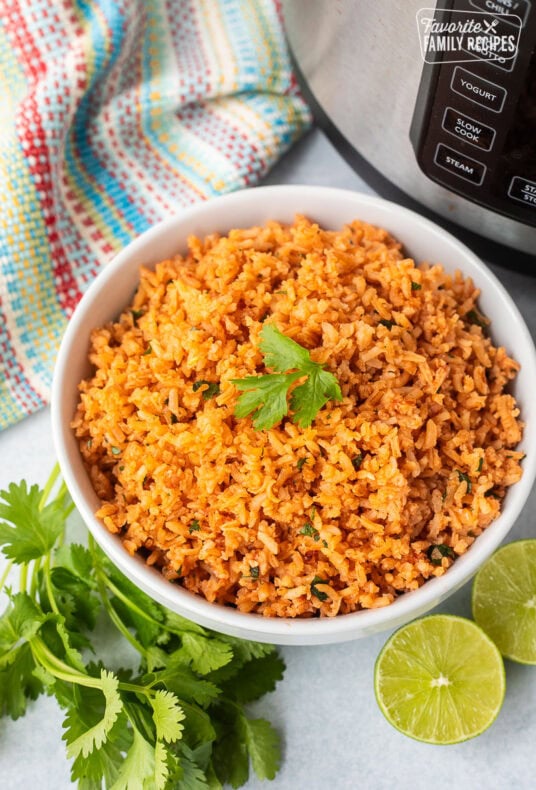 Instant pot Mexican rice in a bowl with cilantro and fresh limes on the side.