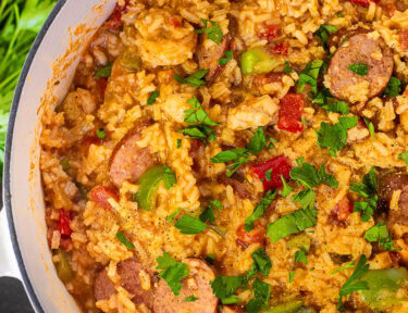 Dutch oven with Jambalaya garnished with fresh parsley and pepper.