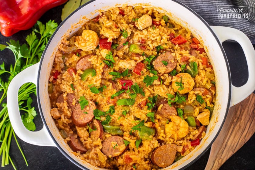 Dutch oven with Jambalaya garnished with fresh parsley and pepper.