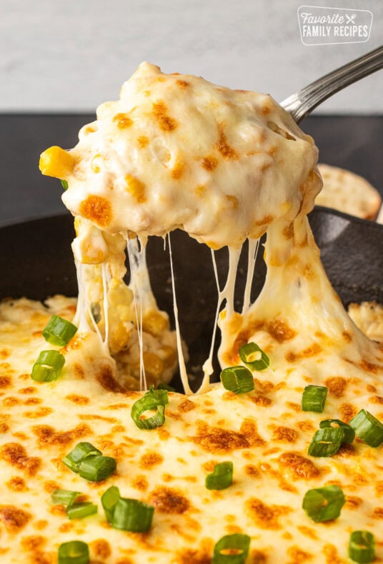 Spoon pulling out Corn Cheese scoop out of a skillet.