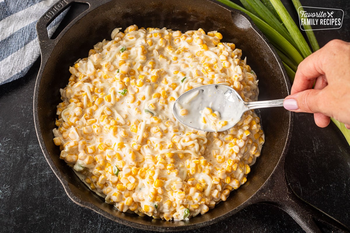 Speaking Corn Cheese mixture into a skillet with a spoon.