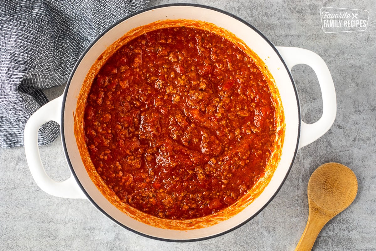 Dutch oven with marinara sauce. Wooden spoon on the side.