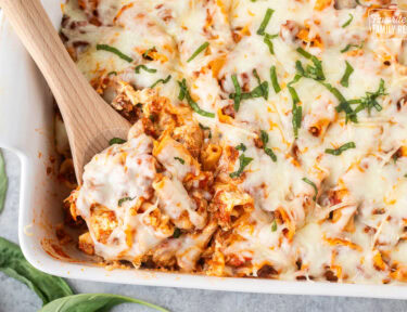 Wooden spoon resting in a baking dish of lasagna casserole