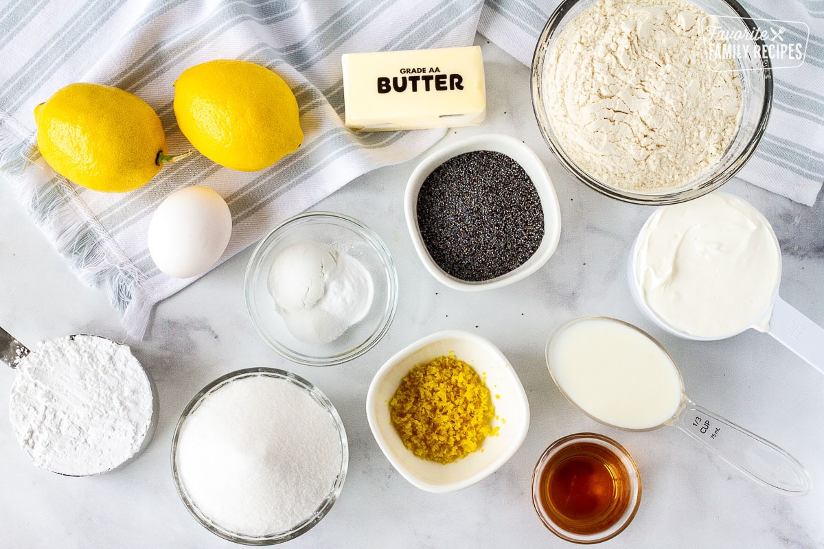 Ingredients to make lemon poppyseed muffins including flour, sour cream, milk, vanilla, lemon zest, lemon juice, poppy seeds, butter, baking soda, baking powder, salt, sugar egg and powdered sugar.