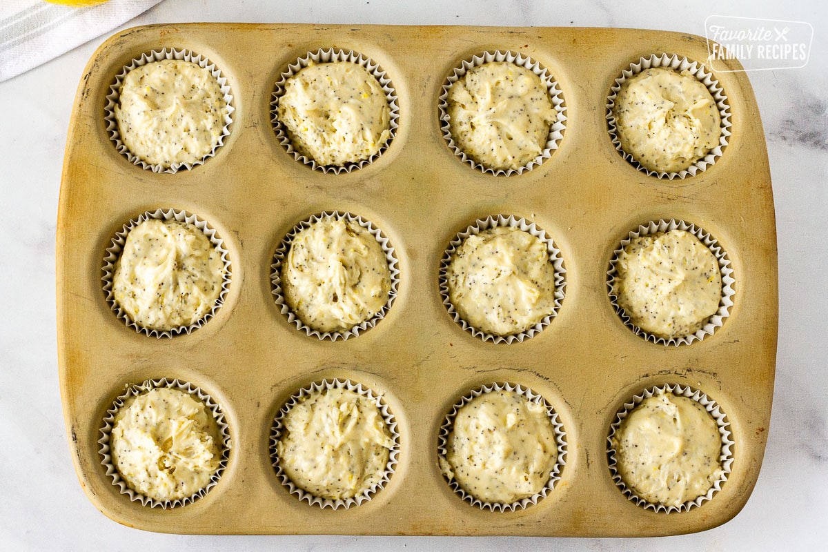 Muffin pan filled with lined unbaked Lemon Poppy Seed Muffins.