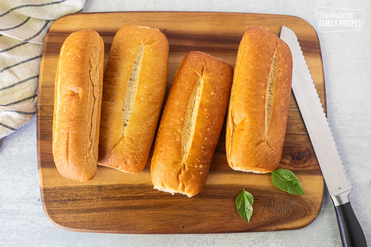 Rolls cut in half on cutting board with knife.