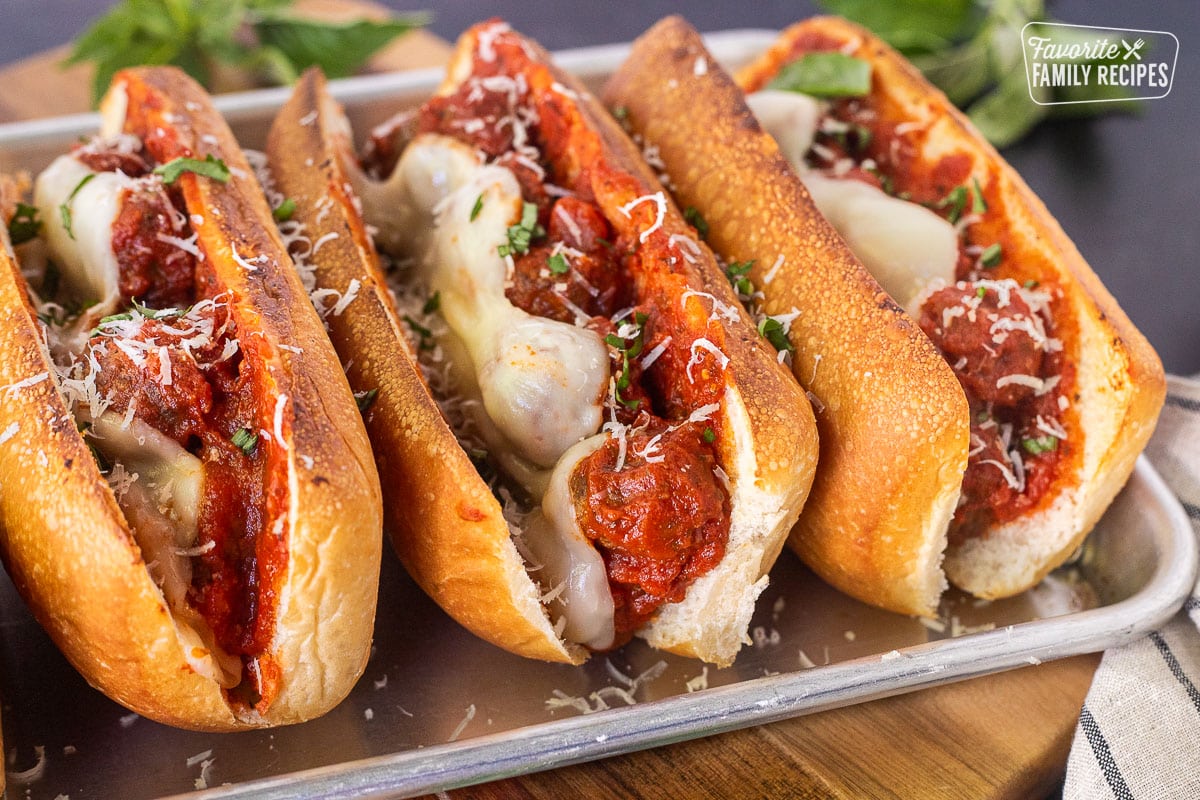 Three Meatball Sandwiches with melted cheese on a toasted roll.