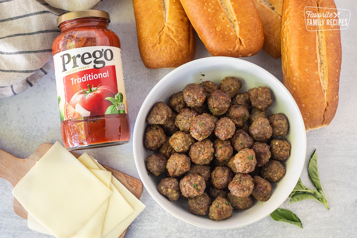 Ingredients to make Meatball Sandwiches including rolls, marinara sauce, provolone cheese and meatballs.