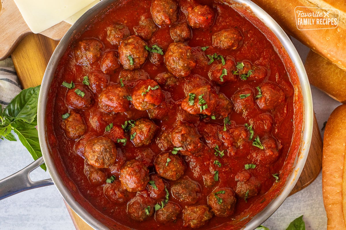 Meatballs in skillet with marinara sauce and basil.