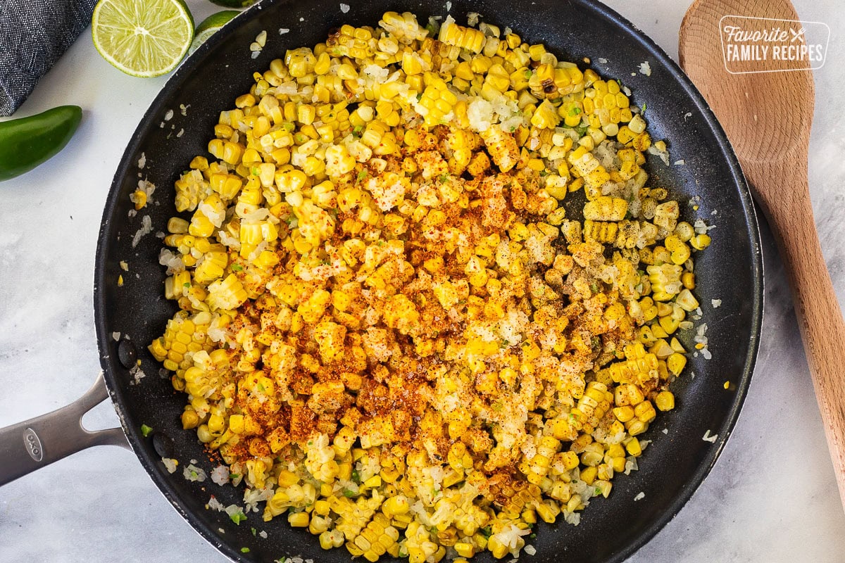 Skillet with seasoning on grilled corn mixture.