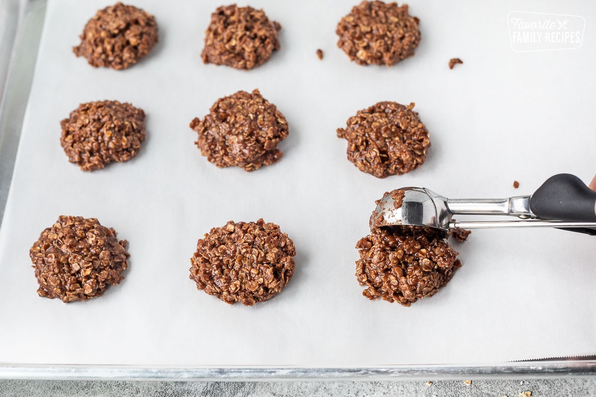 Portioning no bake cookie from a cookie scoop onto a cookie sheet lined with parchment paper.