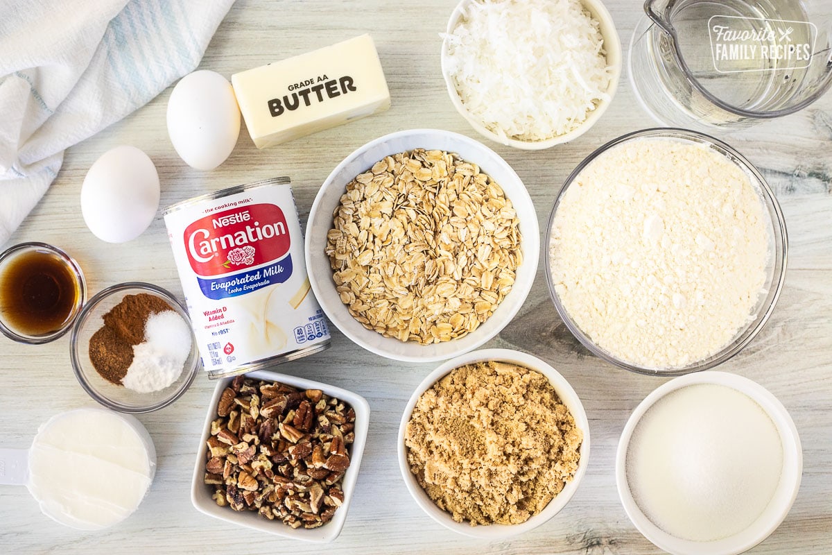 Ingredients to make Oatmeal Cake including oatmeal, flour, oatmeal, brown sugar, sugar, pecans, evaporated milk, coconut, butter, eggs, cinnamon, baking powder, salt, nutmeg, vanilla and shortening.