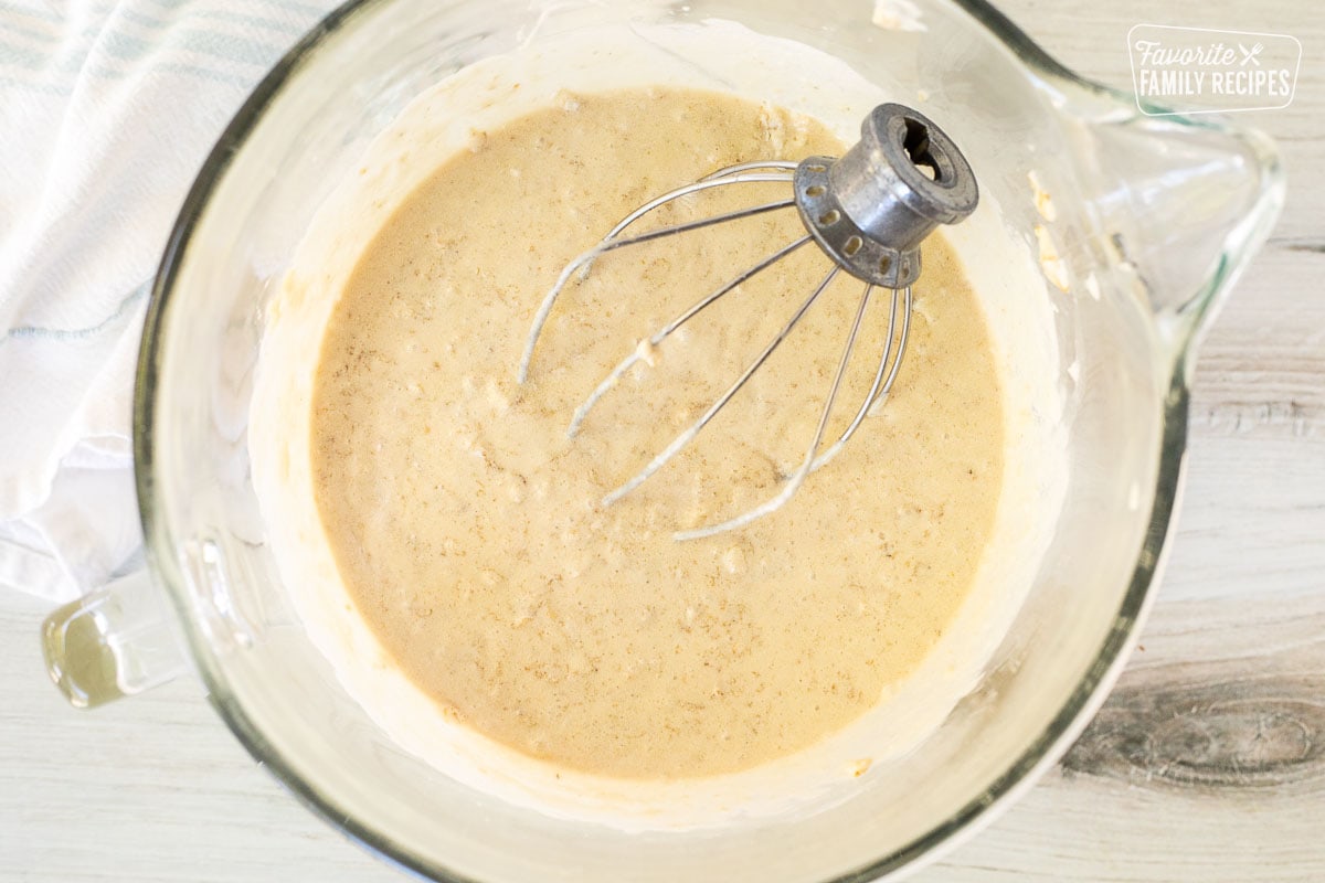 Glass mixing bowl with oatmeal and cake base. Whisk attachment resting in the mixing bowl.