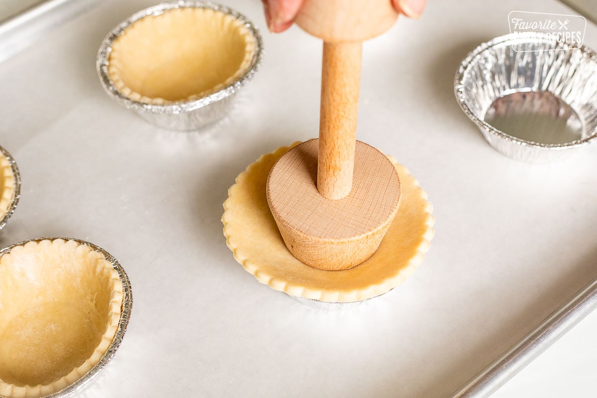 Pressing down pastry dough into pie tins.