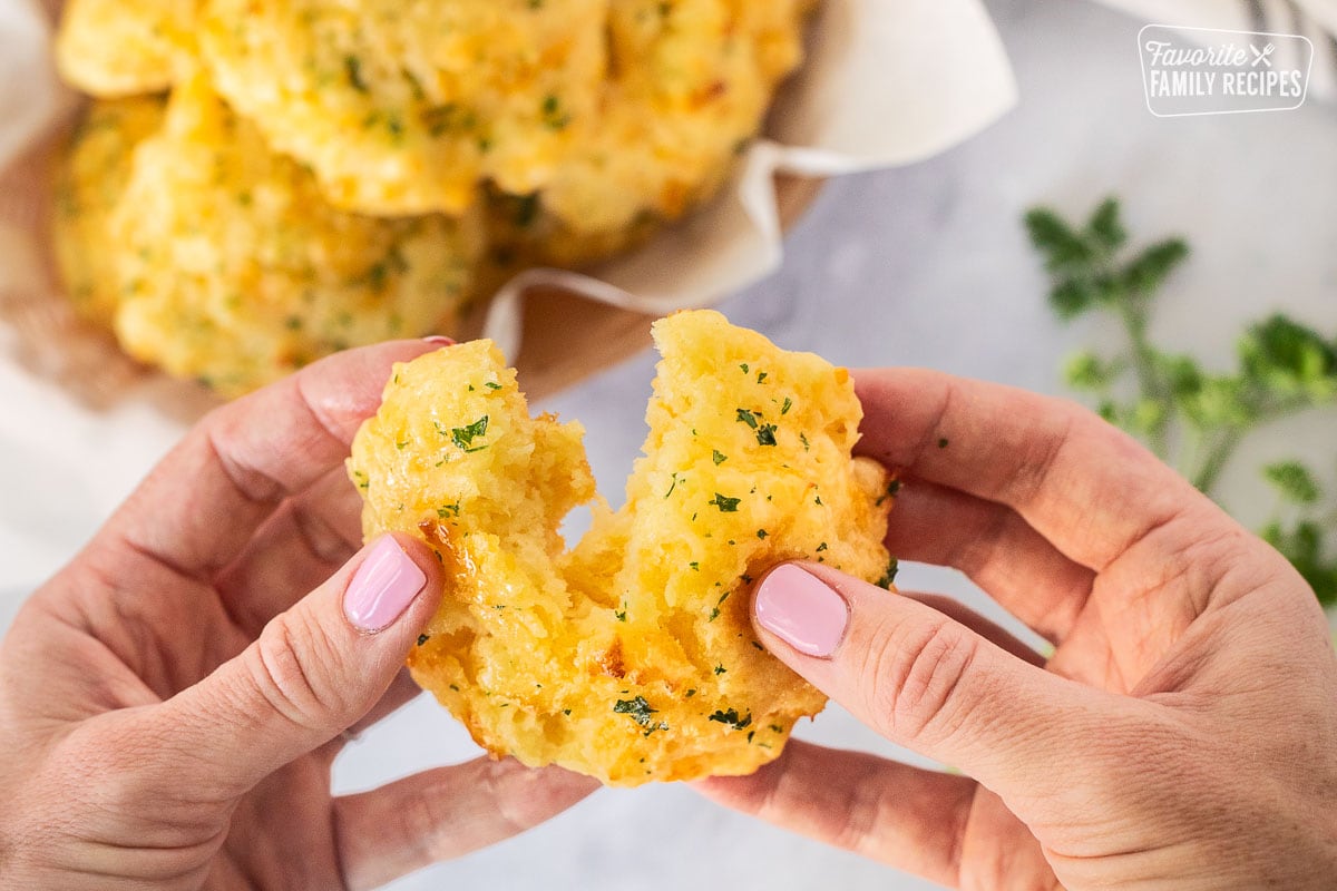 Hands pulling apart a Cheddar Bay Biscuit.