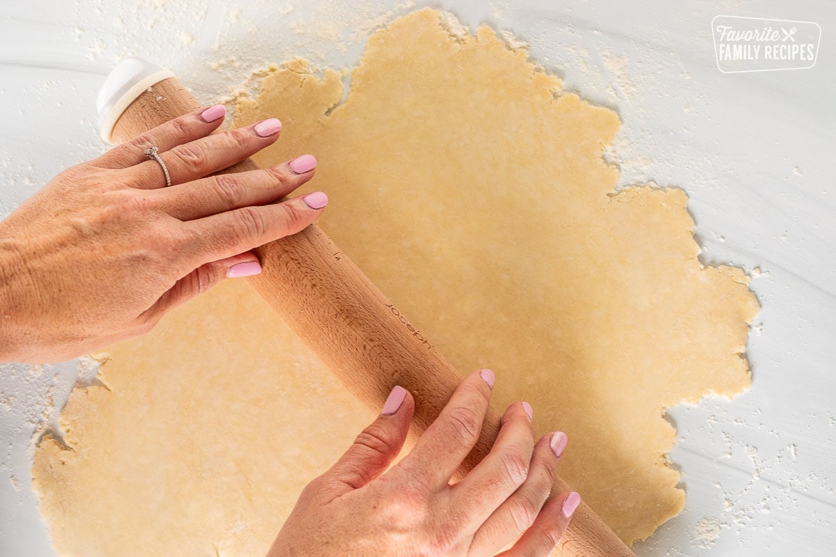 Rolling out pastry dough on floured surface.