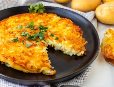 Rosti on a plate garnished with parsley and a cut out with a fork.