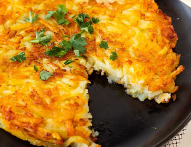 Rosti on a plate garnished with parsley and a cut out with a fork.