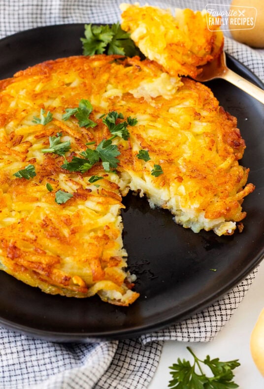 Rosti on a plate garnished with parsley and a cut out with a fork.