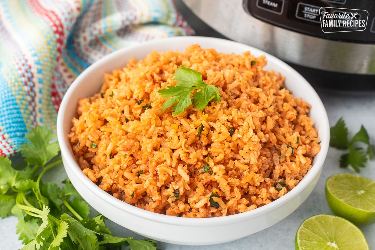 Instant pot Mexican rice in a bowl with cilantro and fresh limes on the side.