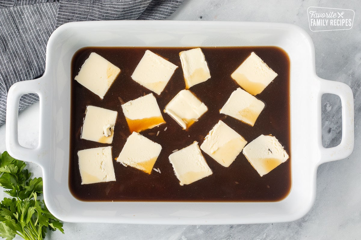 Casserole dish with beef broth, rice and slices of butter.