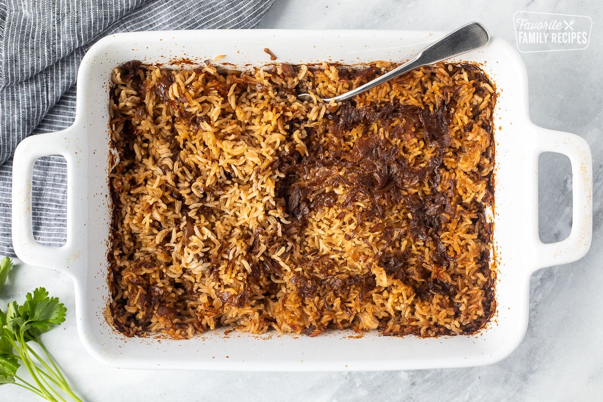 Casserole dish with cooked stick of butter rice with a fork resting in the dish.