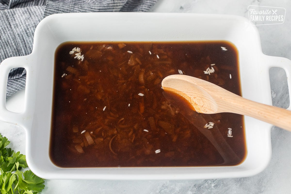 Stirring beef soup mixtures in a casserole dish of rice.