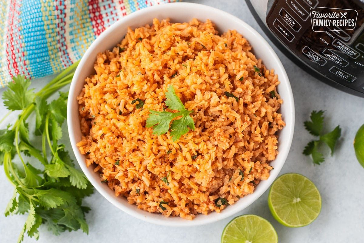 Instant pot Mexican rice in a bowl with cilantro and fresh limes on the side.